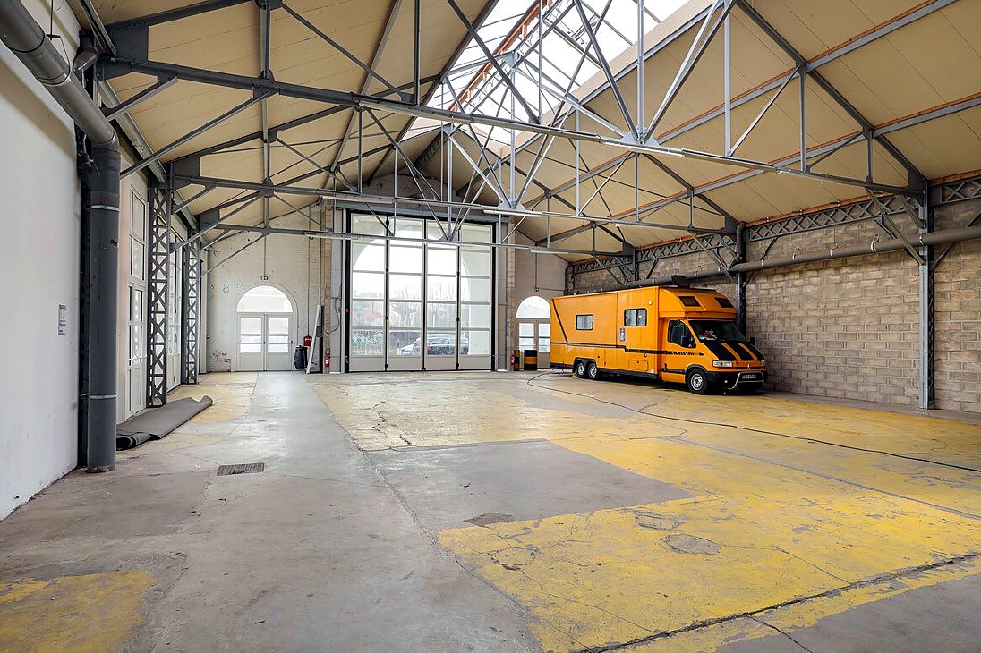 La Petite Halle d'EURĒKA 34 : halle à charpente métallique et verrière, murs de brique, véhicule stationné à l'intérieur